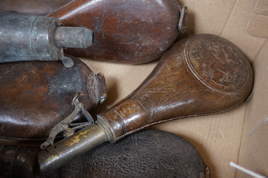 Three gun-sized copper powder flasks, two of which are embossed, together with four leather shot bags each with sprung chargers, two iron and two brass examples, one of which is embossed with a hunting scene (7)